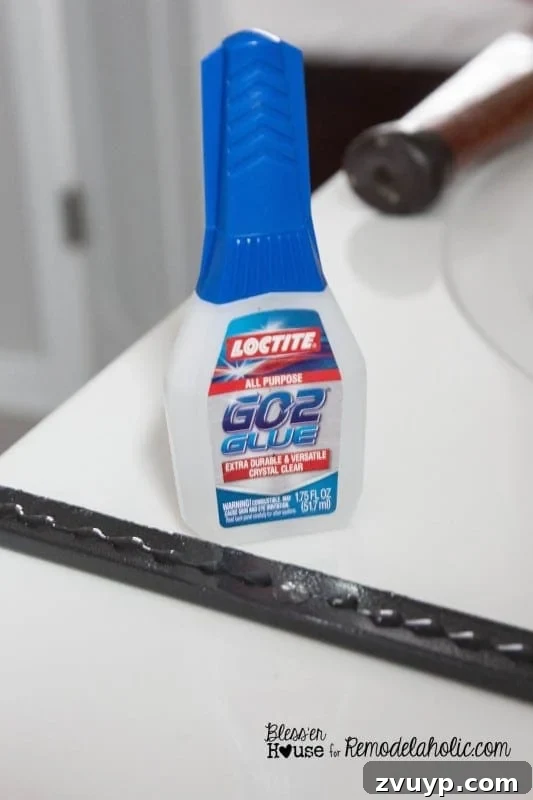 Applying Loctite GO2 Glue to the back of a black polystyrene moulding piece.