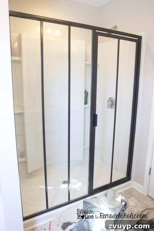 Attaching a vertical polystyrene moulding piece to the glass shower door, checking alignment with a level.