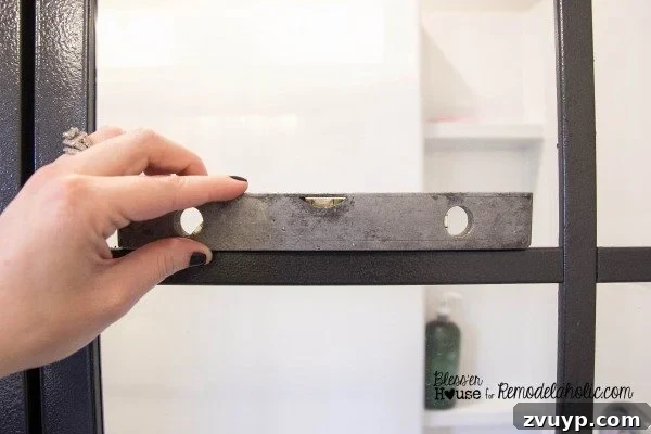 Installing horizontal polystyrene moulding pieces on the shower door, using a level for accuracy.