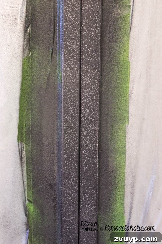 Second coat of hammered black spray paint on a shower door frame, showing progress.