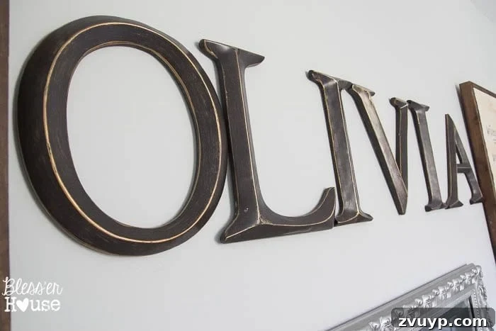 En Pointe Perfection: Her Ballerina Bedroom Makeover 31 Wooden letters spelling 'Olivia' on a wall between DIY sheet music signs in a girl's ballerina bedroom.