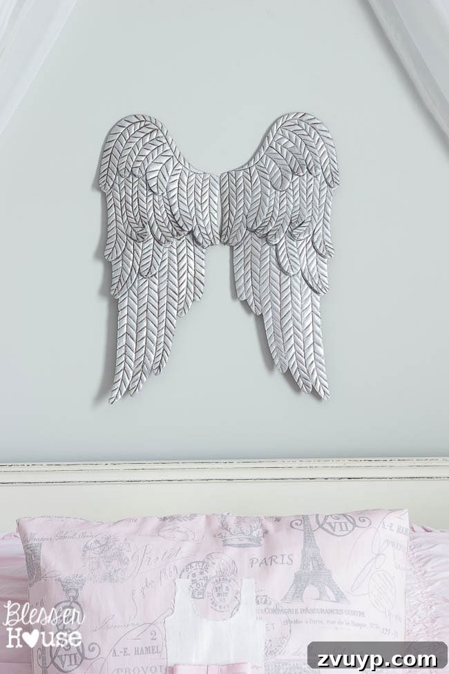 En Pointe Perfection: Her Ballerina Bedroom Makeover 10 Close-up of the aged metal angel wings and a DIY applique pillow, showcasing detail in a girl's room.