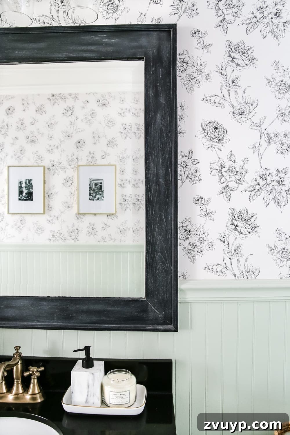 black dry brushed bathroom mirror frame in a powder room with black and white floral wallpaper