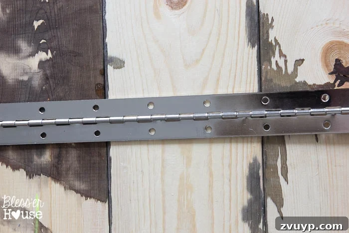 Upcycled Door Knob Towel Hooks 5 DIY Antique Door Knob Towel Rack | Bless'er House: Drilling the hinge into place to connect the wooden planks for the towel rack.