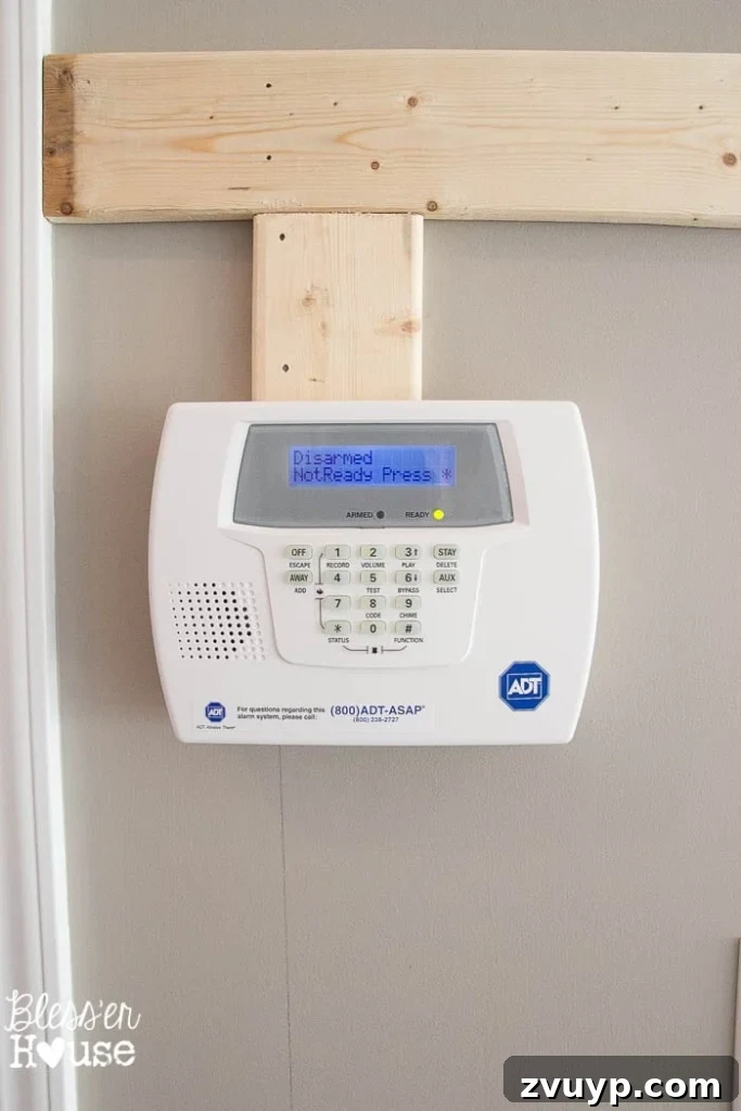 Effortless & Affordable Board and Batten DIY 14 Fitting a batten board around a security system keypad, demonstrating obstacle cutting technique