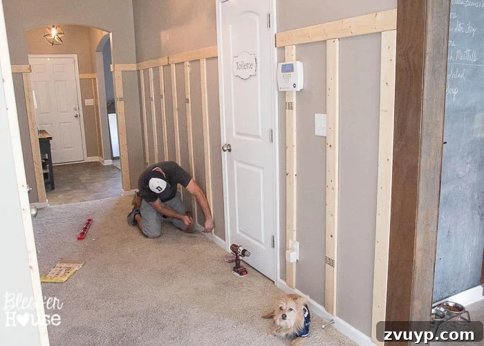 Effortless & Affordable Board and Batten DIY 18 Nailing vertical battens to the wall with a dog supervising the DIY project