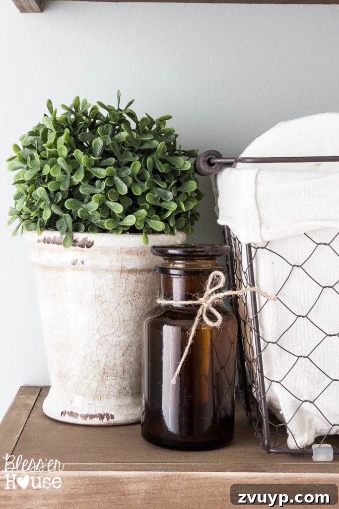 Chic Modern Farmhouse Bathroom Remodel Tour 11 Creative decor on rustic shelves, including a repurposed apothecary bottle, adding farmhouse charm.