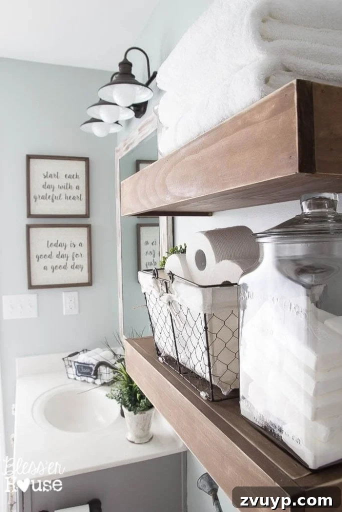Chic Modern Farmhouse Bathroom Remodel Tour 12 Stylish display of towels and repurposed apothecary bottles on floating shelves in a modern farmhouse bathroom.