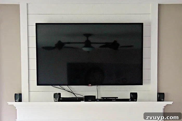 Elevate Your Mantel: Smart Ways to Conceal Electronics 3 Before shot of a fireplace mantel with a TV, showing visible speakers, cords, a PlayStation, Blu-ray player, and digital antenna, highlighting the need for electronic concealment.