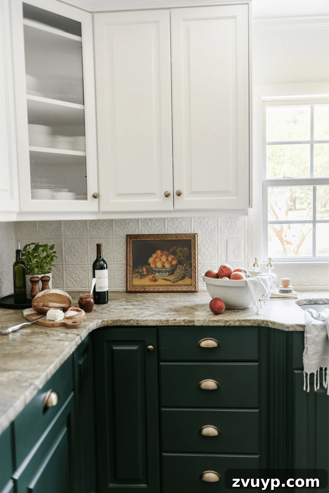 white and green kitchen cabinets with antique gold kitchen cabinet pulls pressed tin backsplash and bowl of peaches on countertop