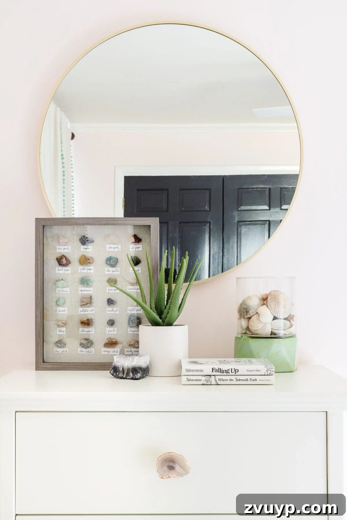 white dresser with agate slice drawer pulls in a little girl's bedroom with round mirror and shadow box rock collection on top