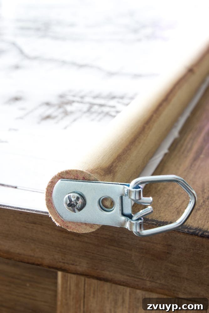 DIY Vintage Scroll Map 5 Attaching D-ring hangers to DIY map | Step-by-step guide to installing D-ring picture hangers on the wooden dowel for your vintage pull-down map. Essential for secure and level hanging. Simple DIY for home decor.