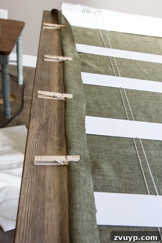 Burlap Roman Shades A Clever Blind Transformation 9 Fabric edges being folded over and secured with clothespins, demonstrating the 2-inch allowance for hemming during the DIY Roman shade process to create a clean finish.