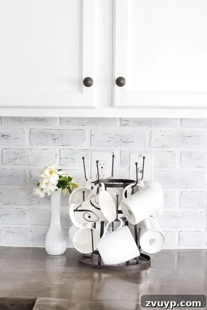 Flawless Cabinets: Paint Your Kitchen Like a Seasoned Pro 15 Close-up of newly painted white kitchen cabinets with a DIY whitewashed brick backsplash. Affordable kitchen renovation ideas.