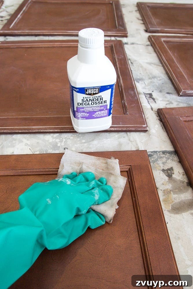 Flawless Cabinets: Paint Your Kitchen Like a Seasoned Pro 7 Applying deglosser to kitchen cabinet doors, a key step to paint without sanding for a durable finish. Learn this DIY cabinet painting technique.