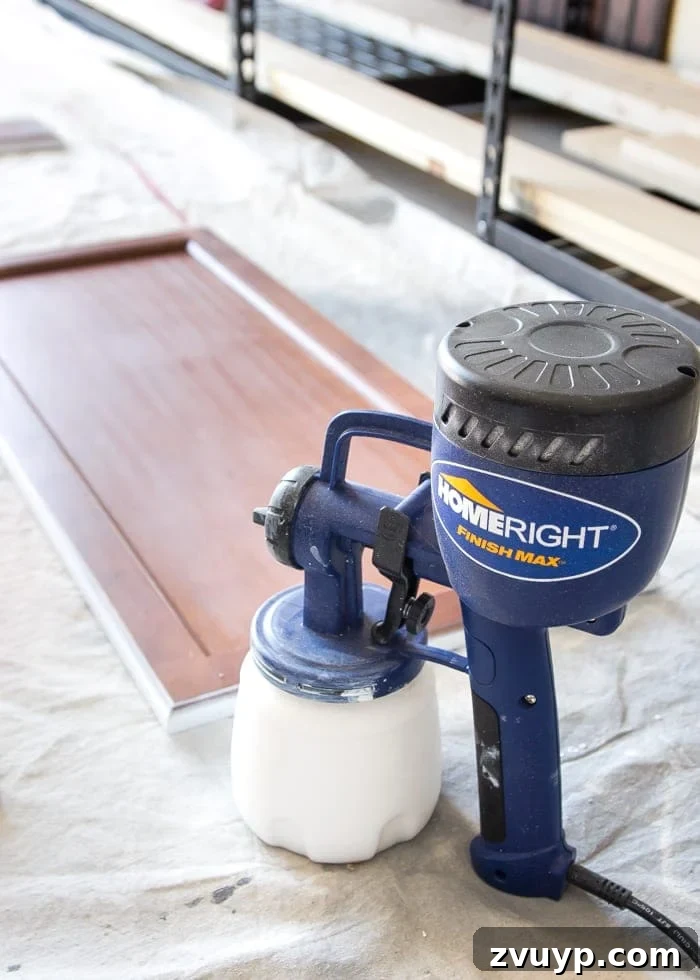 Flawless Cabinets: Paint Your Kitchen Like a Seasoned Pro 8 Priming the back of a kitchen cabinet door with a paint sprayer for a smooth finish. Step-by-step guide to durable cabinet painting.