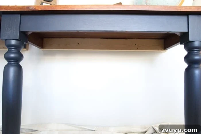 Transforming a Kitchen Table into Wall Desks ORC Week 3 Update 5 Close-up view of the 2x4 support beam securely screwed into the wall underneath the repurposed desk, showcasing robust construction.