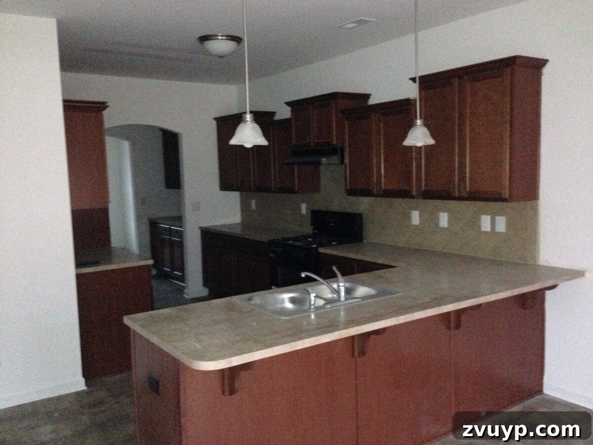 Three Years, One Home: The Transformation Tour 9 Kitchen before makeover: dim, dark space with builder-grade brown cabinets, awaiting a bright modern farmhouse transformation.