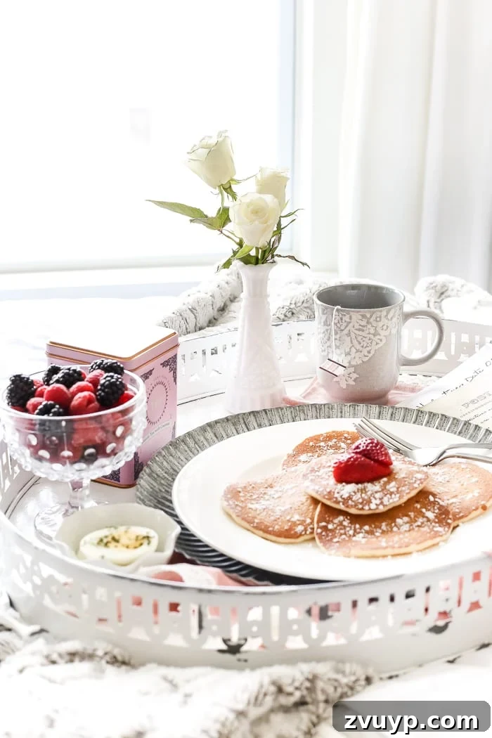 Close-up of a perfectly styled Valentine's Day breakfast in bed setting with the DIY tray, food, and cozy textiles.