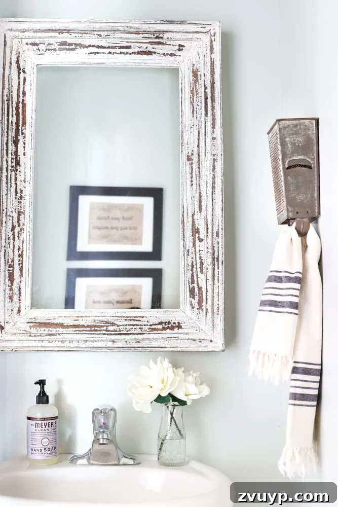 Transform Your Builder Home with Farmhouse Style 20 A vintage box grater cleverly repurposed as a rustic towel rack in a farmhouse bathroom, highlighting creative antique utilization.