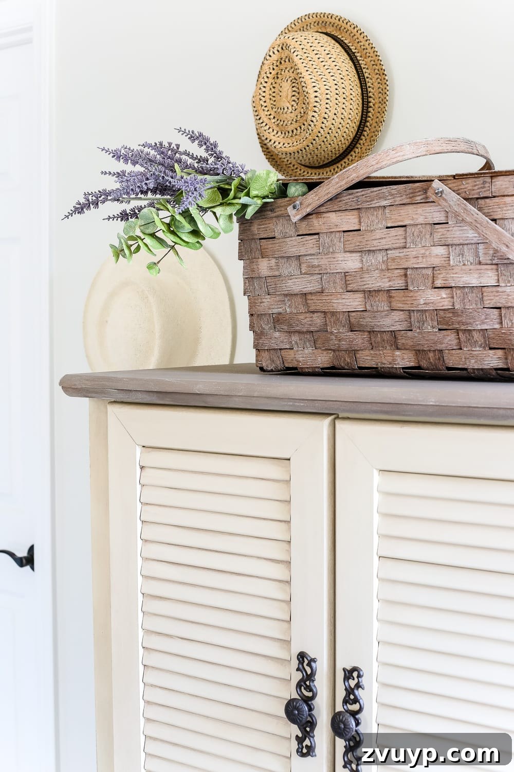Close-up of the charming armoire with decorative hats above it, adding character.