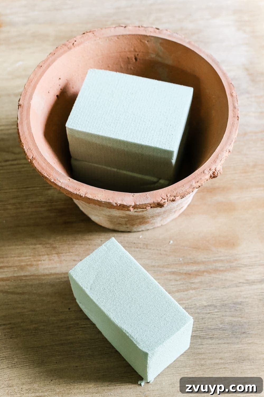 Craft Your Own Olive Topiary 6 Securing two dry floral foam blocks with hot glue in the base of a terracotta planter pot for a DIY topiary.