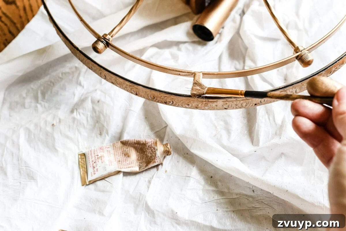 Regal Radiance Antique Gold Crystal Fixture Reimagined 8 Using an artist brush to apply Rub 'n Buff to intricate details and hard-to-reach areas of the light fixture for a precise finish.