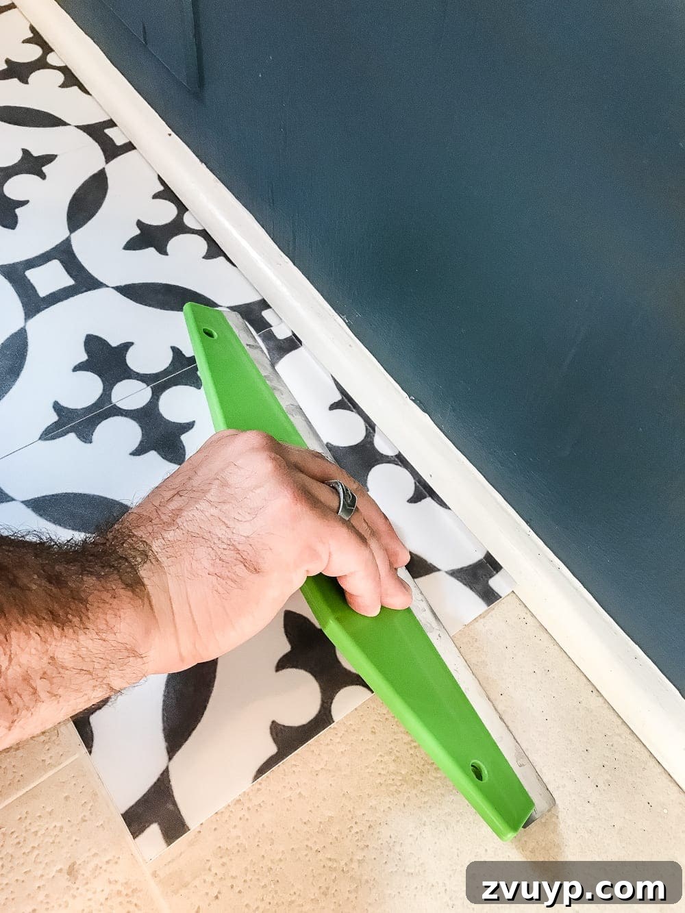 Moroccan Vinyl Tile Floor DIY 5 Installing the first row of peel and stick vinyl tiles in a laundry room, using existing lines as a guide.