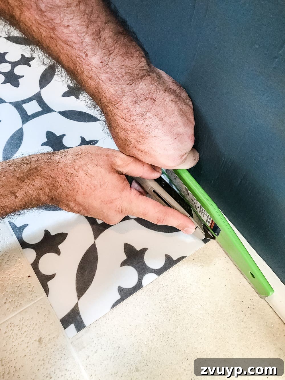Moroccan Vinyl Tile Floor DIY 6 Demonstration of smoothing a peel and stick vinyl tile with a wallpaper tool during installation.