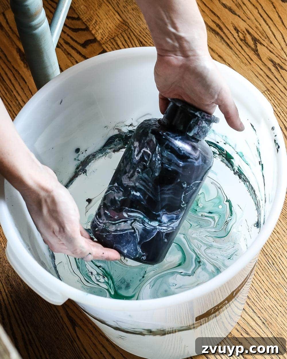 Marbled Wonders for a Haunted Welcome 8 Dipping a black spray-painted jar into nail polish water for marbling effect