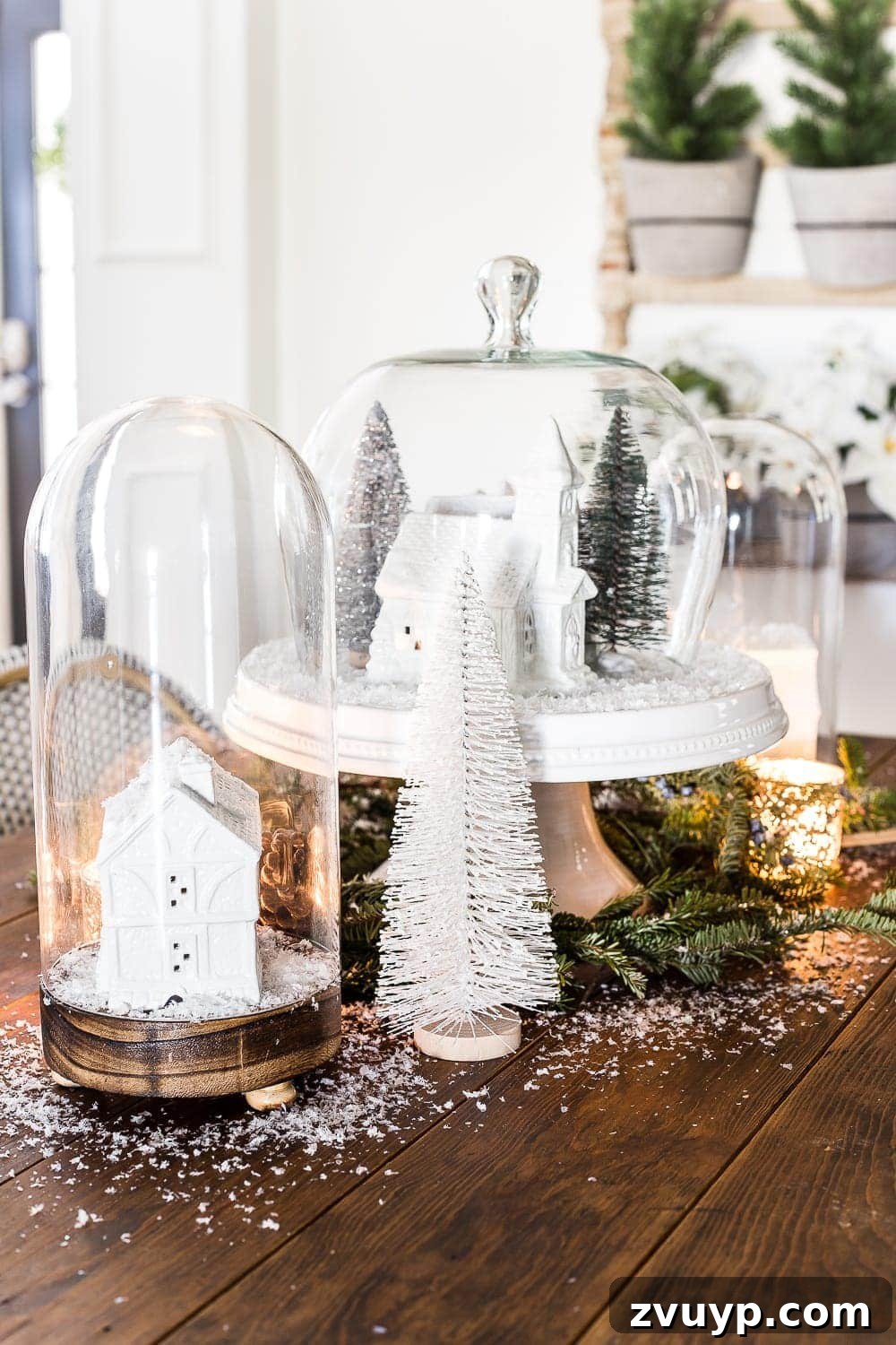 Yuletide Village Snow Globe Showpiece 6 Elegant white Christmas village under a glass cloche, creating a serene holiday display. #FestiveHome #WinterVignette