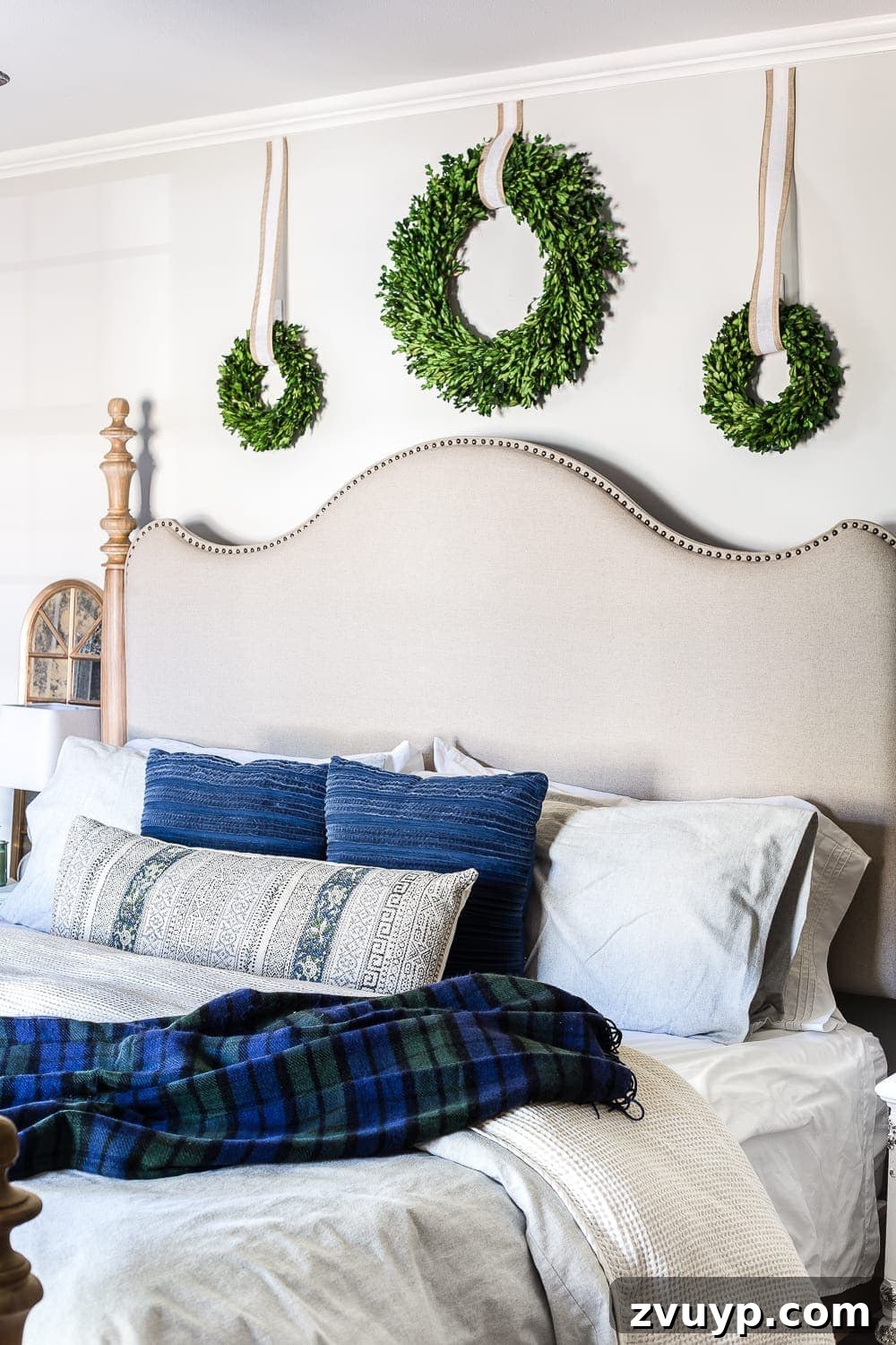 Cozy Blue and Neutral Christmas Sanctuary 3 Elegant Preserved Boxwood Wreaths in a Blue Christmas Bedroom | blesserhouse.com - Detailed view of preserved boxwood wreaths above a bed, contributing to a serene blue and neutral Christmas and winter bedroom theme.