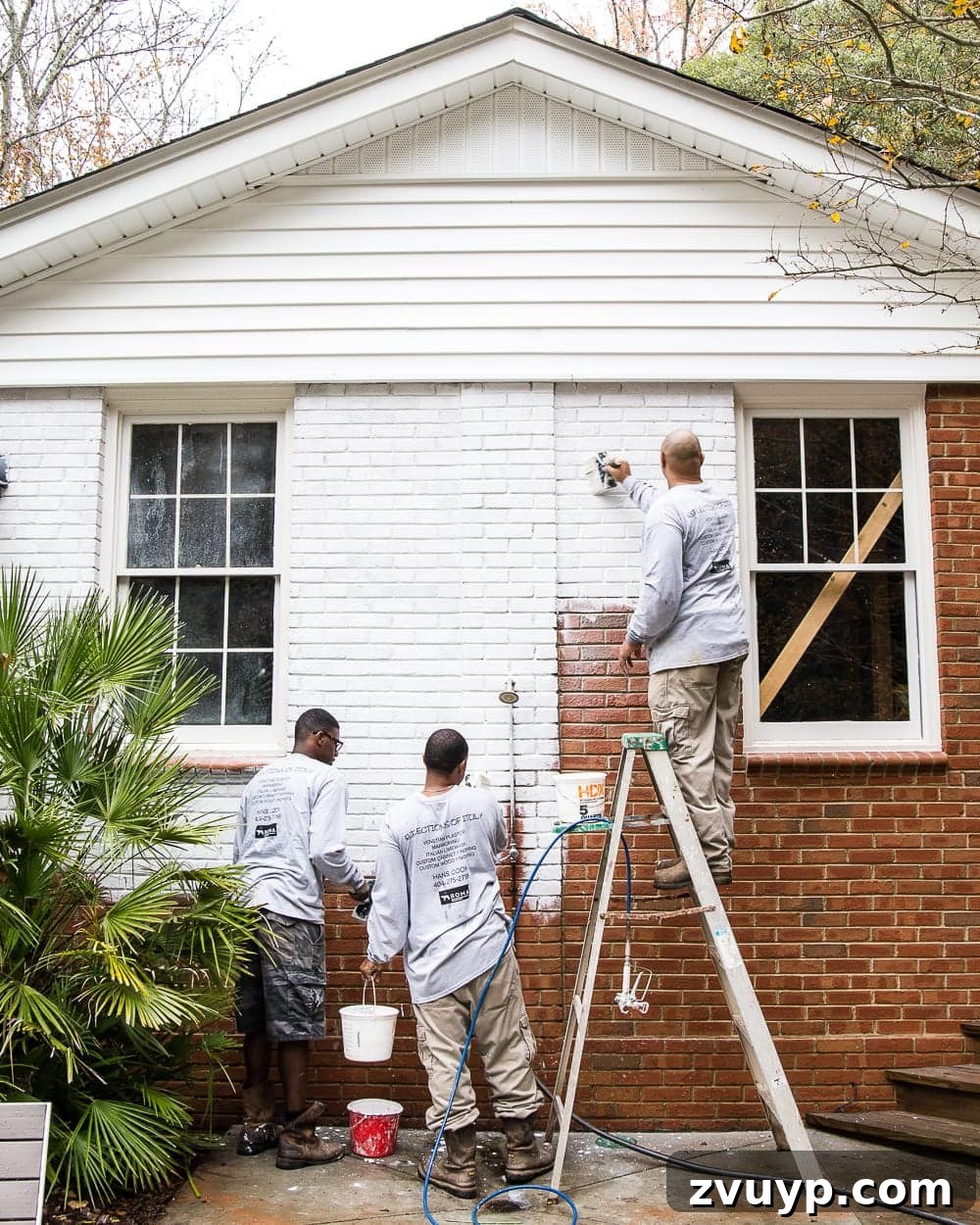 Limewash Magic: Our Brick Exterior Transformed 7 Hand brushing Romabio Bianco White limewash paint on a brick exterior