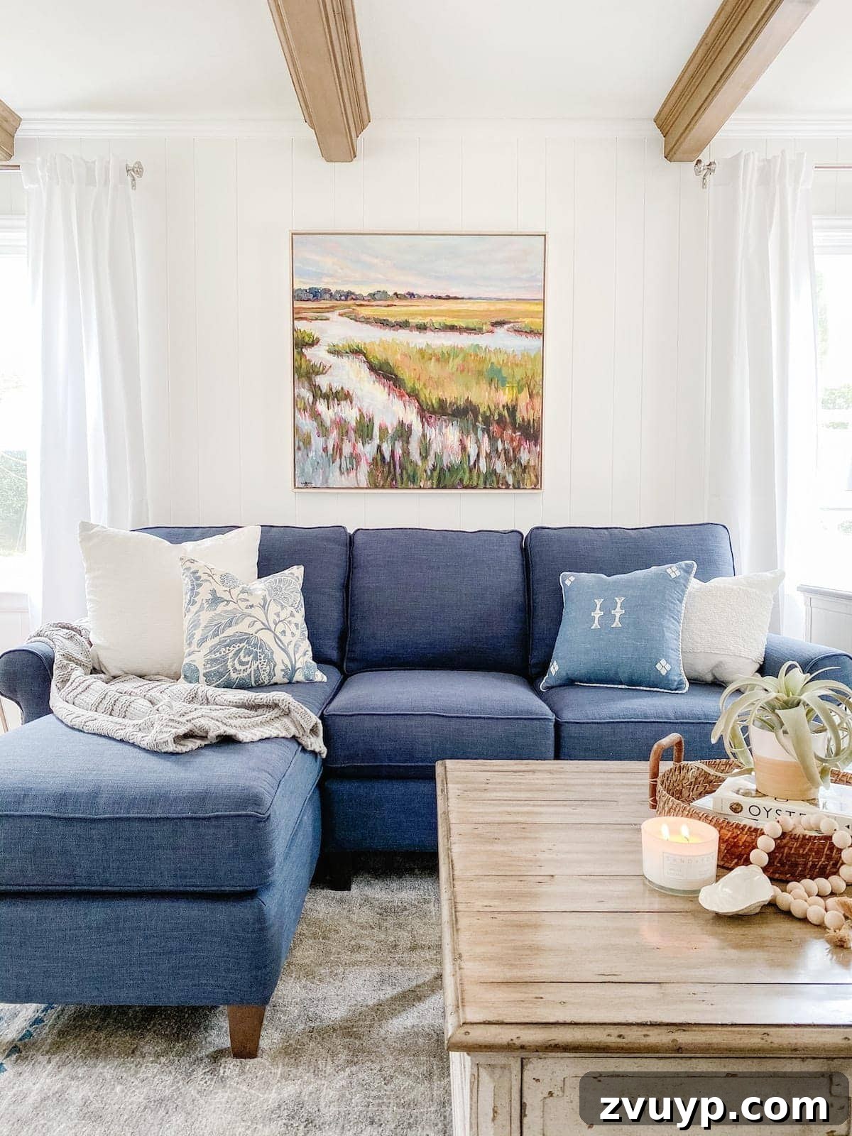 Ageless Interior Design: Lasting Style Principles 13 A bright, coastal-style living room featuring white walls and a comfortable blue sectional sofa, creating a timeless and serene atmosphere.
