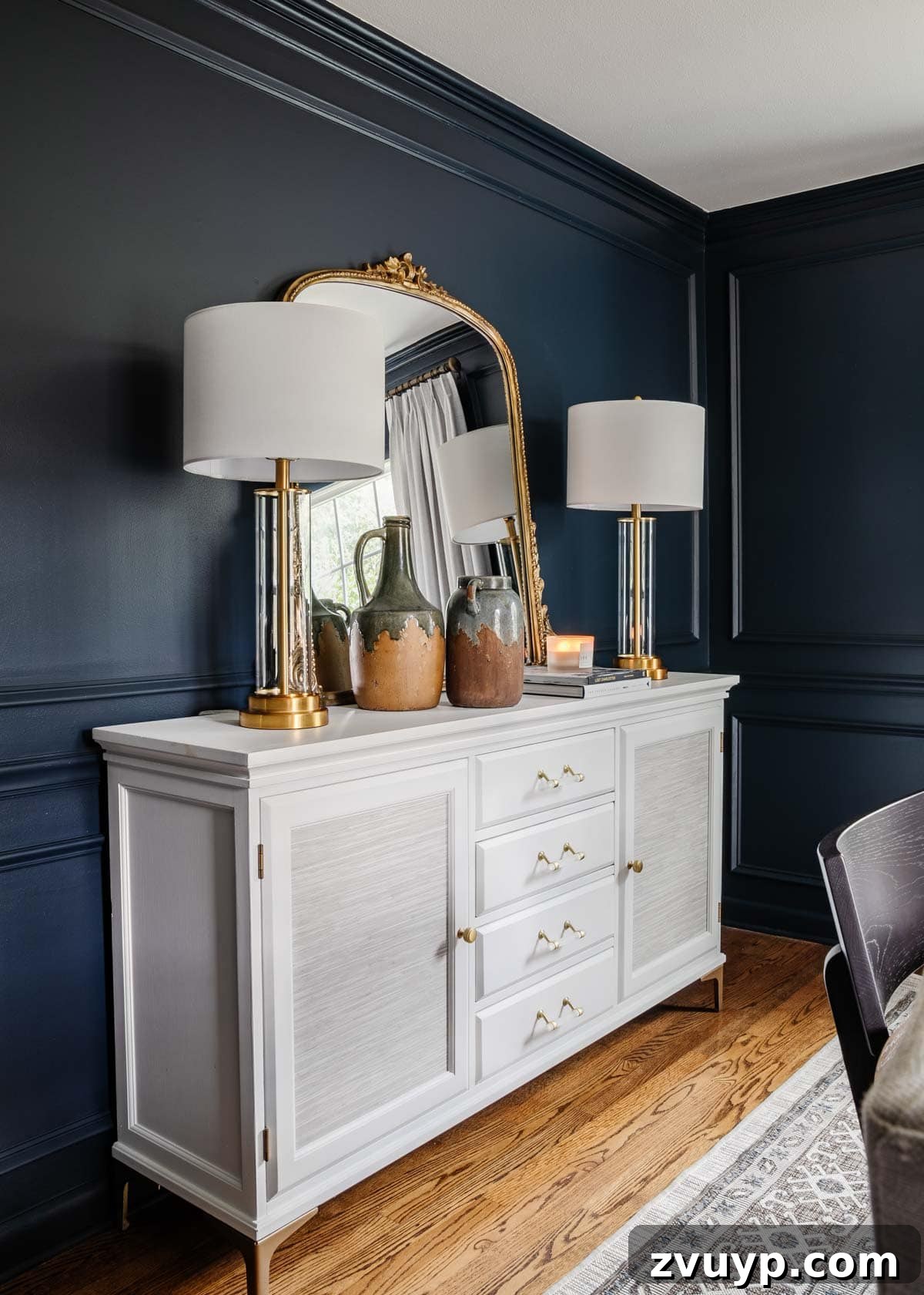 Ageless Interior Design: Lasting Style Principles 16 A stately navy blue dining room featuring a crisp white sideboard and a magnificent gilded mirror, embodying classic and modern traditional style.