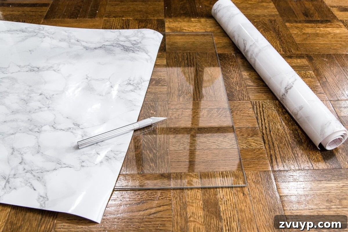 Chic Marble-Effect Coffee Table 6 Applying marble contact paper to a glass table top on the floor