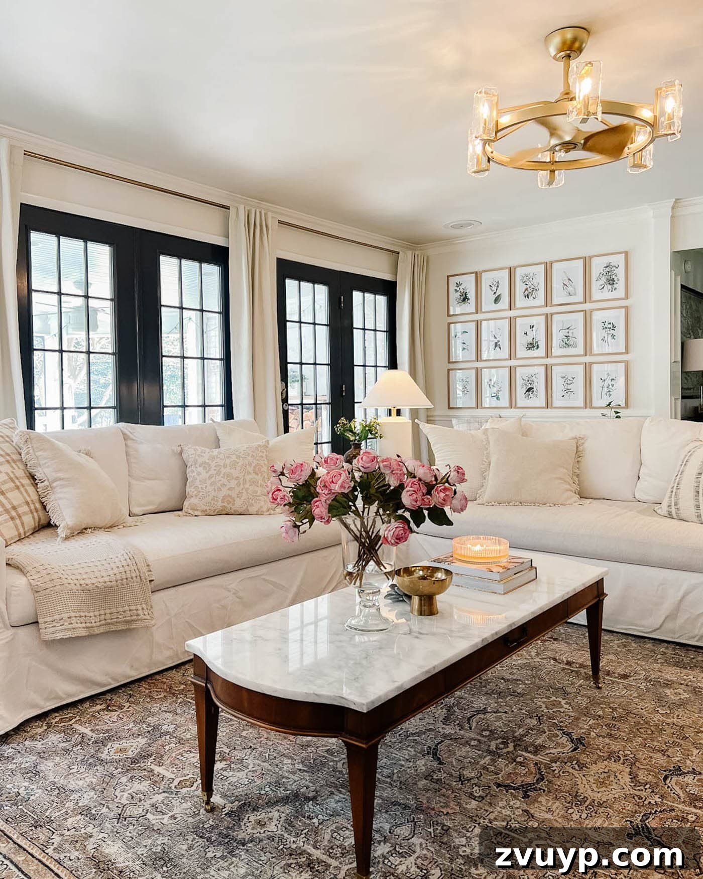 A bright living room with white walls, elegant black French doors, and comfortable white sofas, complemented by a textured rug and a marble-topped coffee table, showcasing balanced lighting.