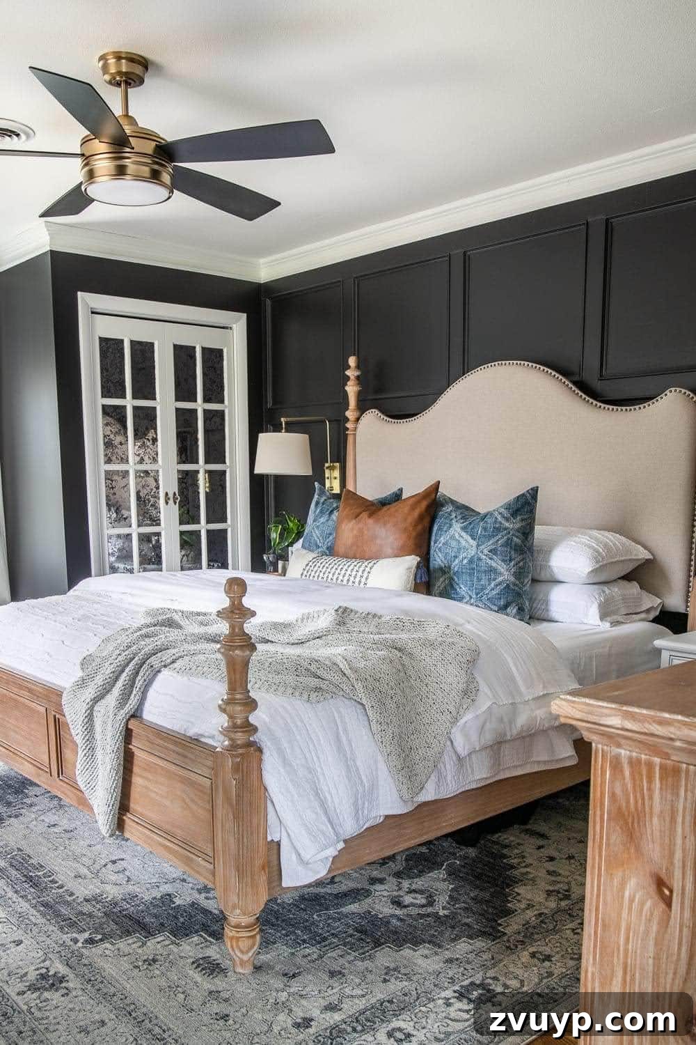 A black bedroom featuring a king-sized bed, white mirrored closet doors, and crisp white bedding, all contributing to an expansive feel in a small space.