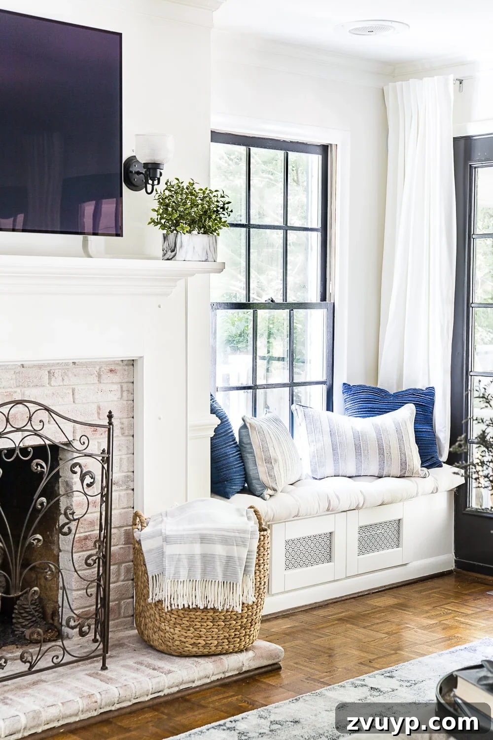 A cozy living room featuring a smart window seat with hidden electronics storage and a limewashed fireplace, emphasizing clutter-free design in a small space.