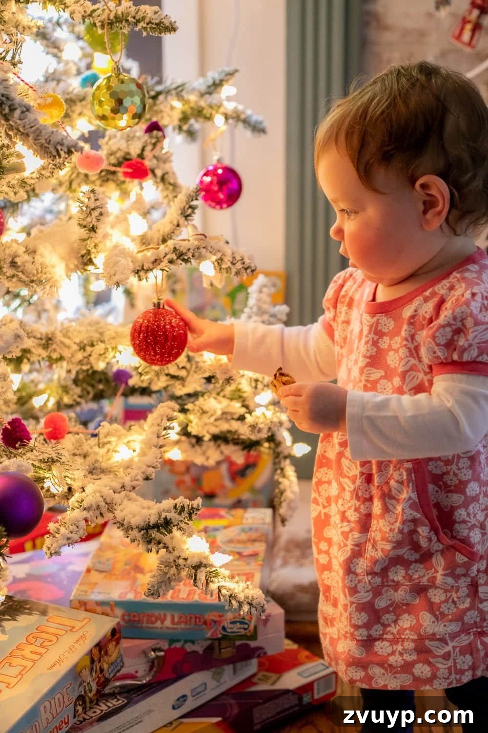 Cozy Christmas Captures: Easy DIY Family Photos at Home 6 Toddler standing mesmerized beside a beautifully lit Christmas tree, capturing a magical and heartwarming holiday moment at home