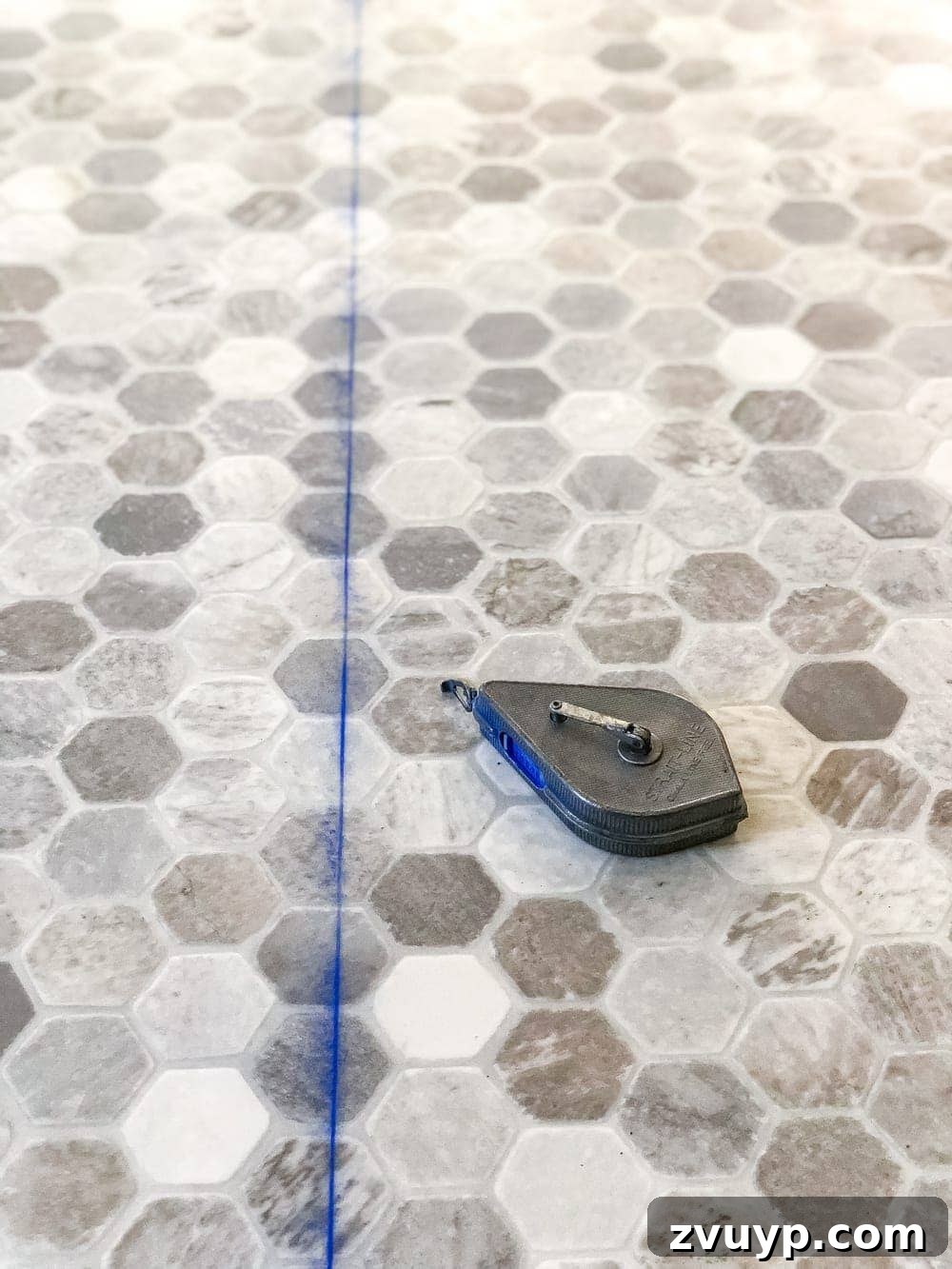 DIY Floor Makeover Seamless Sheet Vinyl Over Tile 14 A person using a chalk line to mark a straight cutting line between two measurements on a large piece of sheet vinyl flooring.