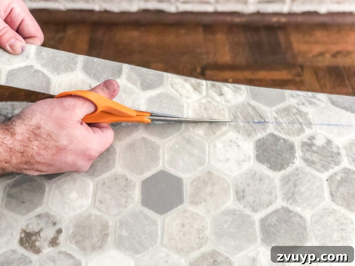 DIY Floor Makeover Seamless Sheet Vinyl Over Tile 15 A person cutting a large sheet of vinyl flooring with sharp scissors, following a marked line for installation.