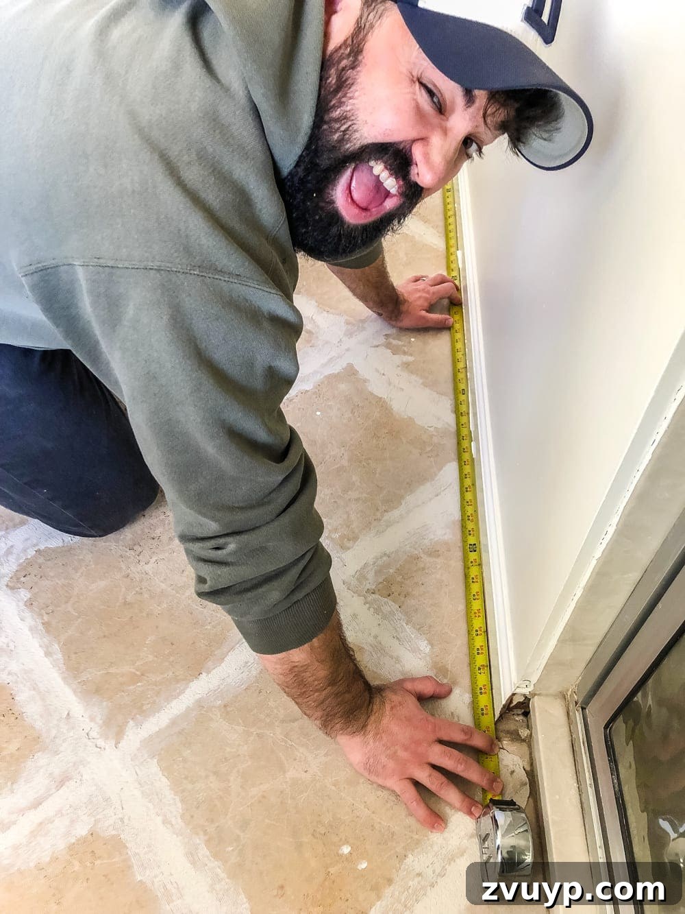 DIY Floor Makeover Seamless Sheet Vinyl Over Tile 10 A person measuring the perimeter of a room with a tape measure, preparing to draw a diagram for the sheet vinyl template.