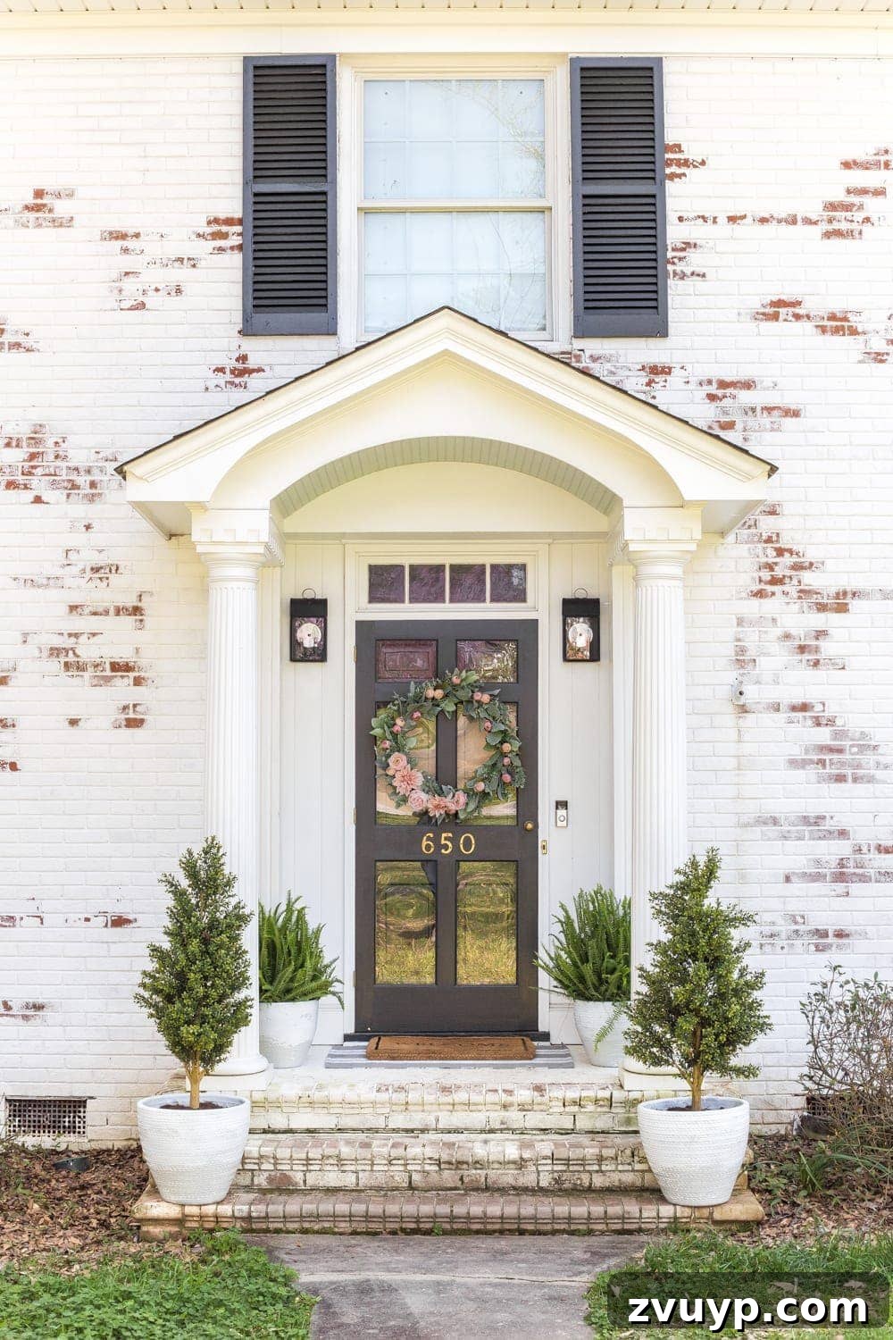 Simple Spring Porch Makeover Ideas 3 Front porch with green plants, a layered doormat, and a glimpse of a limewashed brick wall, ready for spring.