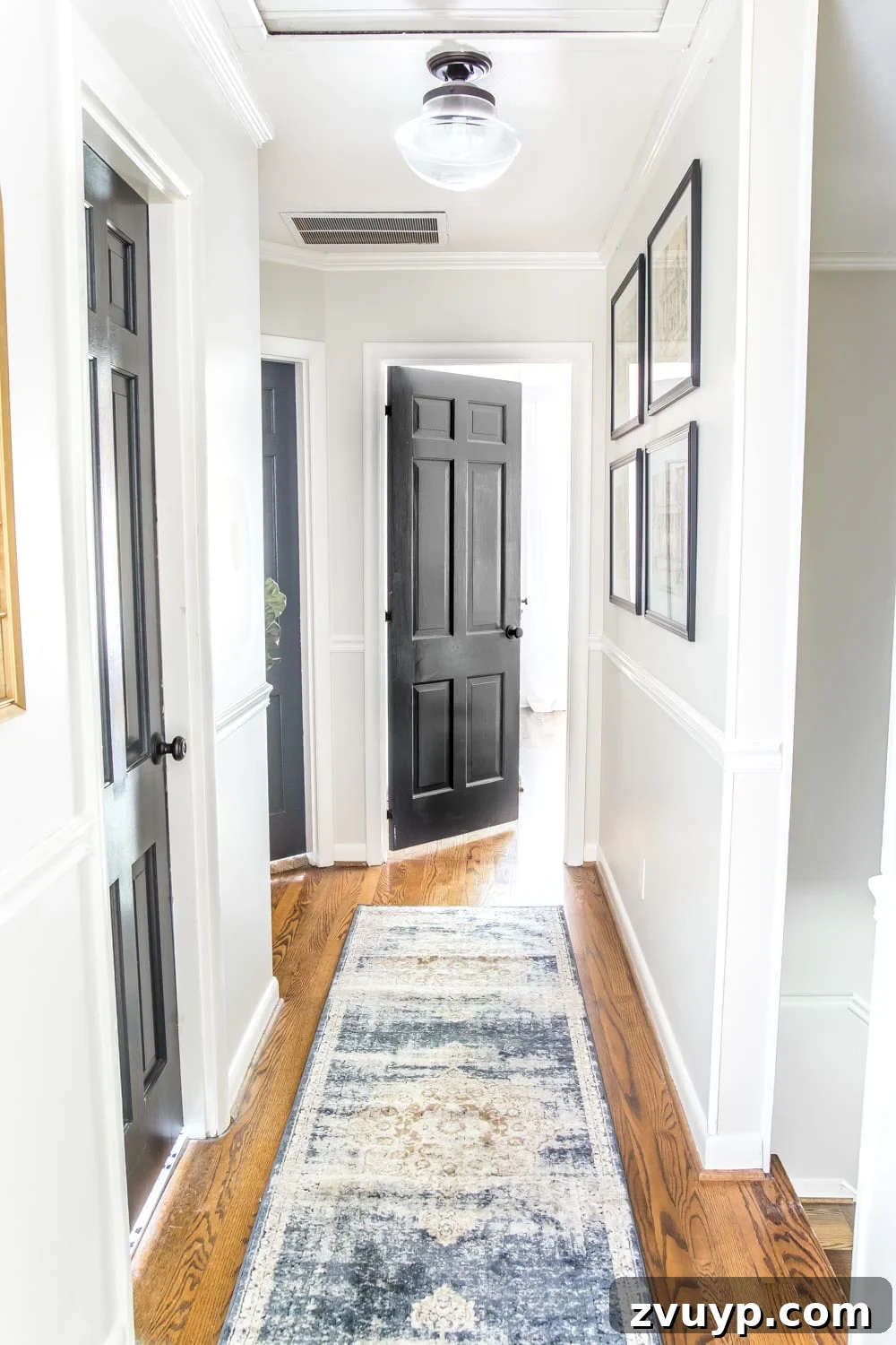 Stylish Solutions for Skinny Hallways 6 light gray painted hallway with dark charcoal doors, a runner, new lighting, and wall decor