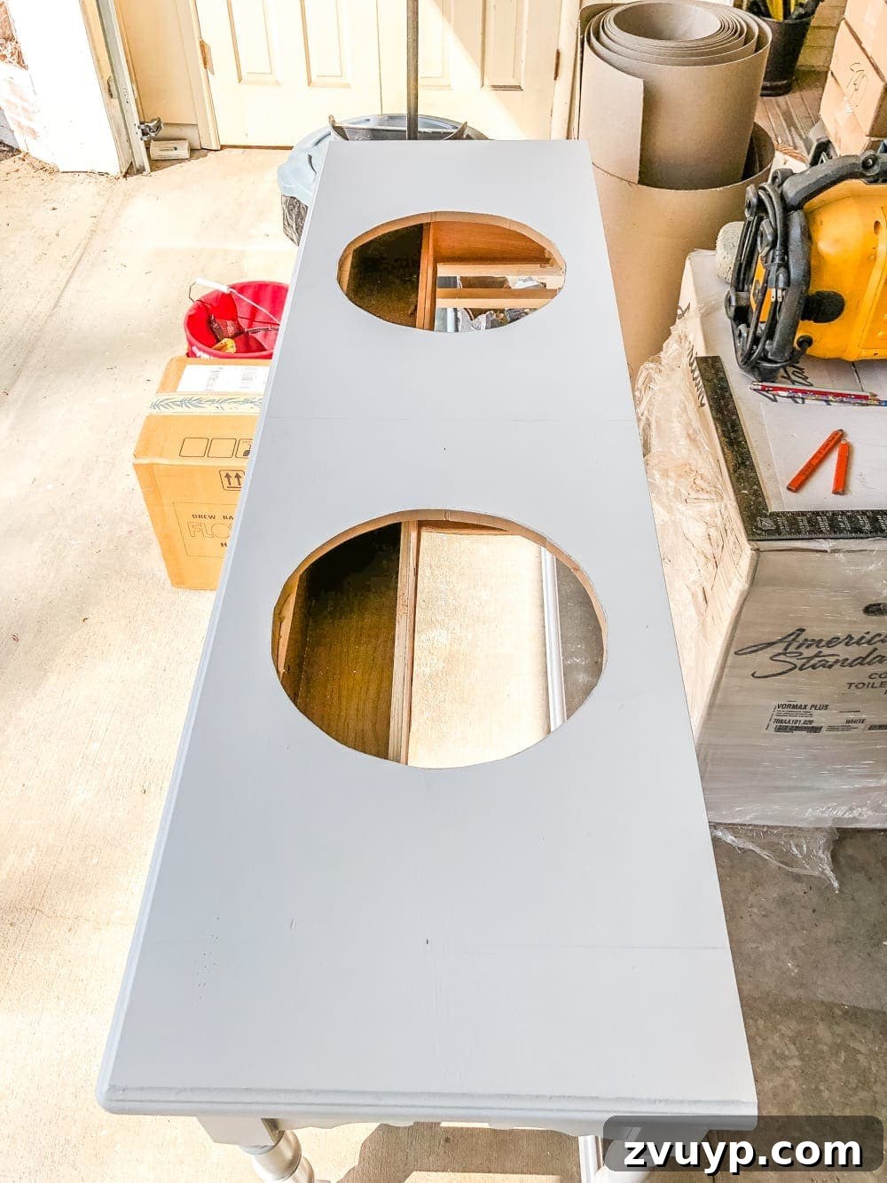 Upgrade Your Console Table to a Stunning Bathroom Vanity 10 Cutting circular sink holes into the vanity countertop using a jigsaw for vessel sink installation.