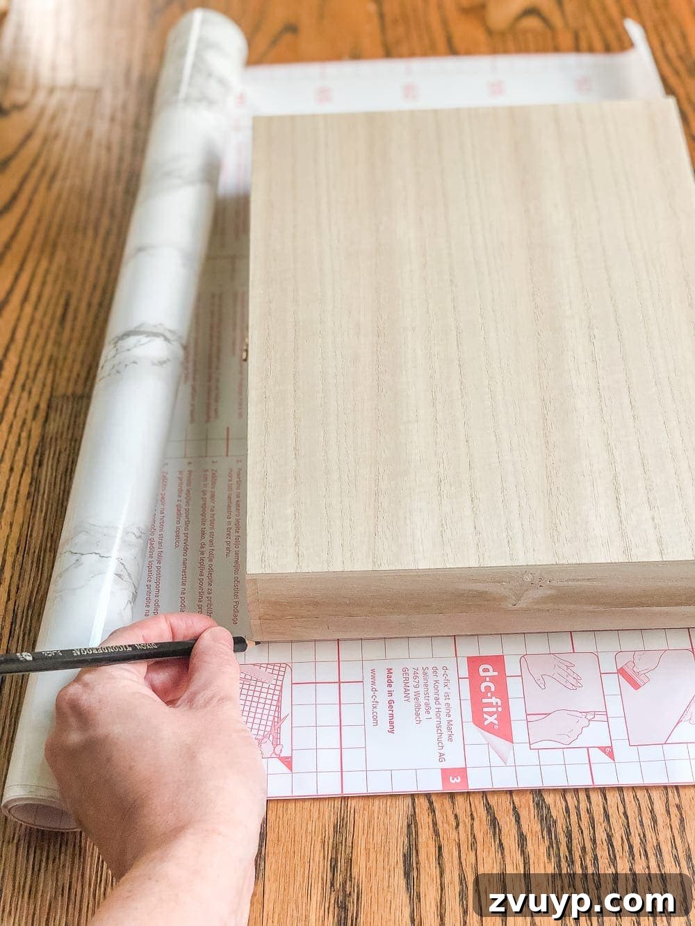 Cigar Box to Chic Faux Marble Remote Organizer 4 Measuring and marking a cigar box onto marble contact paper for a DIY project.