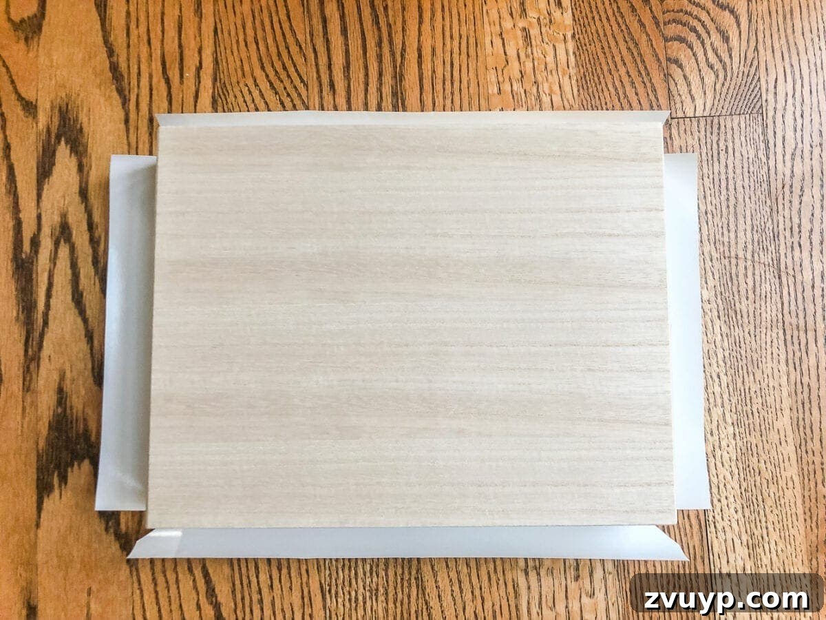 Cigar Box to Chic Faux Marble Remote Organizer 7 Hand applying marble contact paper to a cigar box for a DIY remote control holder, smoothing out bubbles.