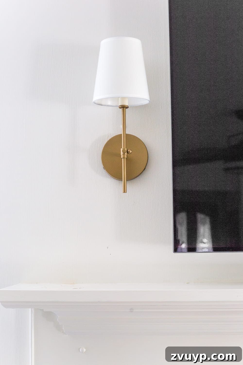 Beyond the Screen: Creative Ways to Style Your TV Area 4 Elegant aged brass sconces on a minimalist mantel, framing the TV beautifully.