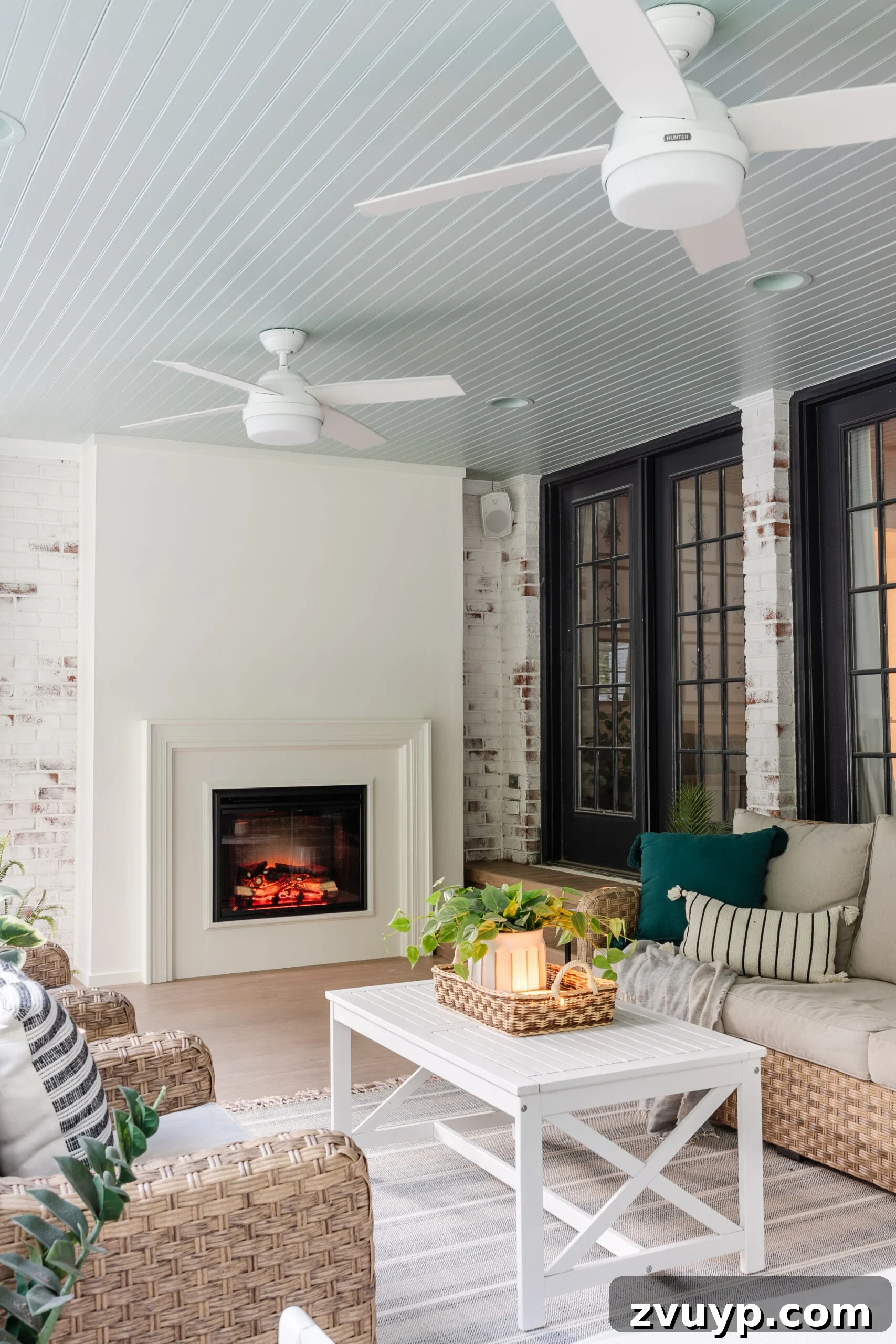20 Handpicked Modern Ceiling Fans to Adorn Your Home 7 Two white outdoor ceiling fans on a porch with a traditional haint blue ceiling and a stylish limewash fireplace, creating a serene outdoor retreat.